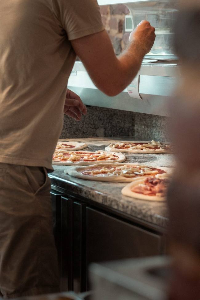 Préparation d'une pizza au comptoir chez Pizz'Ath