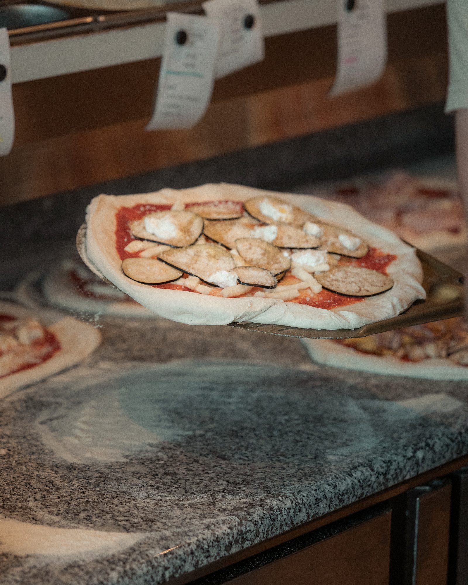 Pizza sur la pelle avant enfournement chez Pizz'Ath